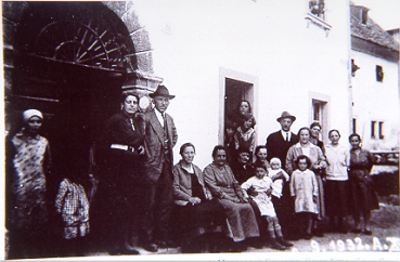 1932. Famiglia Tamussin Bòrtul et al. sull'uscio della casa omonima, di cui è visibile il portale in primo piano. Sullo sfondo, la casa di Céch (225)